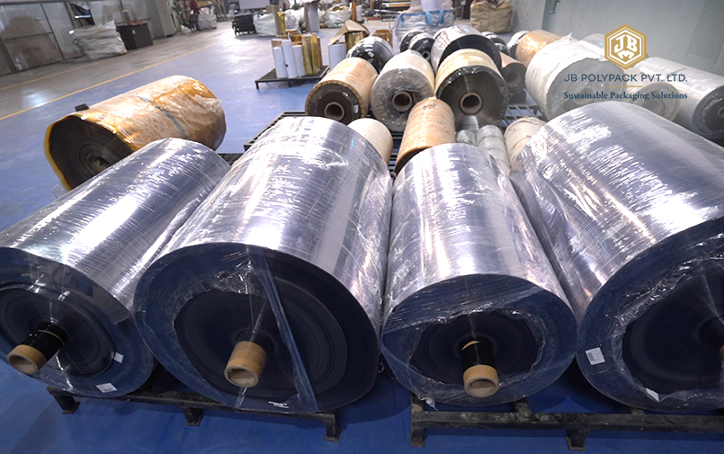 Large rolls of transparent PET sheets stored in a packaging manufacturing facility